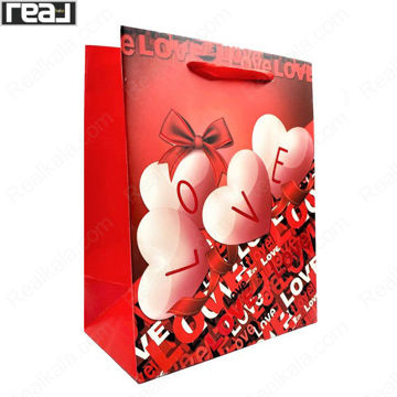 ساک دستی کادویی قرمز با طرح بادکنک‌های قلبی سفید و نوشته LOVE، دارای بند قرمز و ابعاد 22.5 × 18 × 9.5 سانتی‌متر