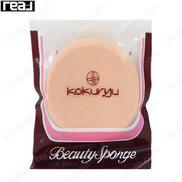 اسفنج آرایشی گرد Kokuryu Beauty Sponge به رنگ هلویی بژ داخل بسته‌بندی شفاف با بخش قهوه‌ای تیره و حاشیه صورتی سفید