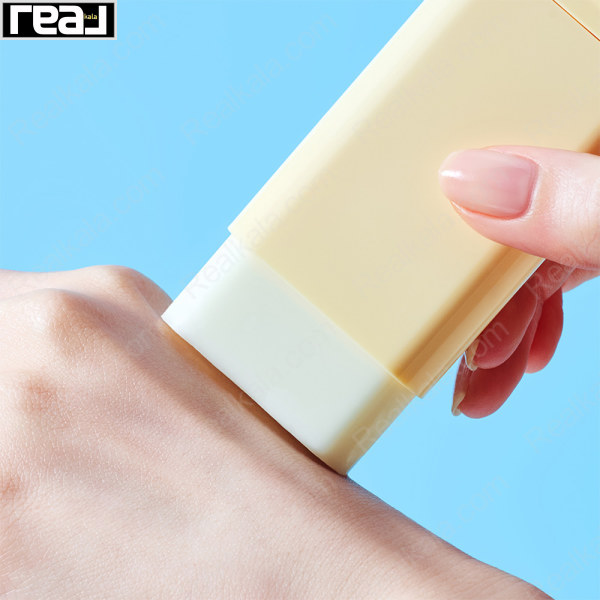 استیک ضدآفتاب زرد در حال کشیده شدن روی پوست دست با پس‌زمینه آبی